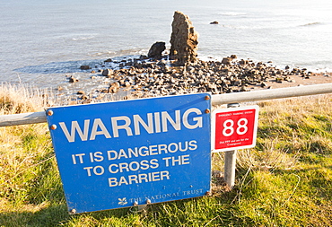 Warning sign above sea stacks on the north east coast at Whitburn, between Newcastle and Sunderland, Tyne and Wear, England, United Kingdom, Europe