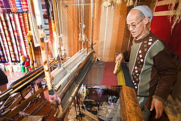 An old man working a loom to weave traditional Moroccan cloth in a souk in Marrakech, Morocco, North Africa, Africa