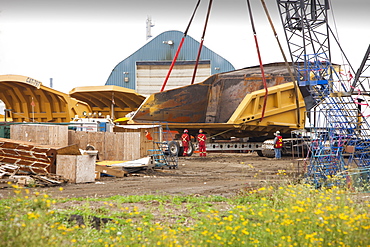 Workers prepare a massive dump truck bucket used in the tar sands mines in Fort McMurray, the centre of the tar sands industry, Alberta, Canada, North America