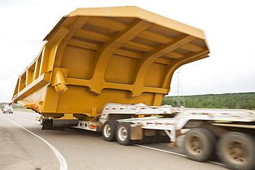 Truck hauls an oversize load, a massive dump truck used in the tar sands mines, on the road towards Fort McMurray, the centre of the tar sands industry, Alberta, Canada, North America