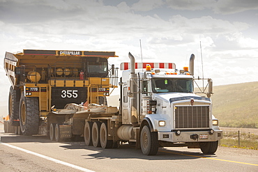 Truck hauls an oversize load, a massive dump truck used in the tar sands mines, on the road towards Fort McMurray, the centre of the tar sands industry, Alberta, Canada, North America