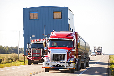 Trucks haul an oversize load of tar sands equipment for a SAGD mine, on the road towards Fort McMurray, the centre of the tar sands industry, Alberta, Canada, North America