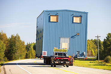 Trucks haul an oversize load of tar sands equipment for a SAGD mine, on the road towards Fort McMurray, the centre of the tar sands industry, Alberta, Canada, North America