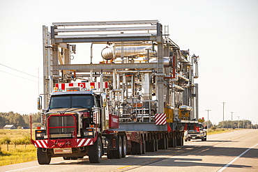 Trucks haul an oversize load of tar sands equipment for a SAGD mine, on the road towards Fort McMurray, the centre of the tar sands industry, Alberta, Canada, North America