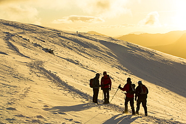 Walkers on Helvellyn in the snow at sunset, Lake District National Park, Cumbria, England, United Kingdom, Europe