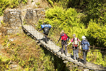 Trekkers crossing a suspension bridge crossing on the Annapurna Base Camp trek, Himalayas, Nepal, Asia