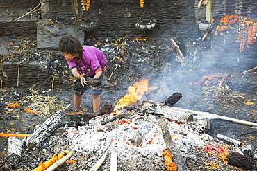 Boy recycling wood after a cremation at the Pashupatinath Temple, a Hindu temple of Lord Shiva on the banks of the Bagmati River, UNESCO World Heritage Site, Kathmandu, Nepal, Asia