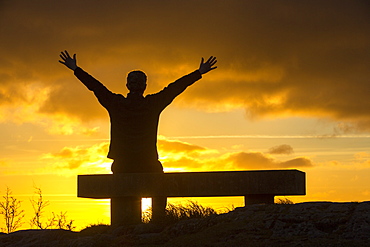 A walker relaxing at sunset on Orrest Head above Windermere, Lake District, Cumbria, England, United Kingdom, Europe