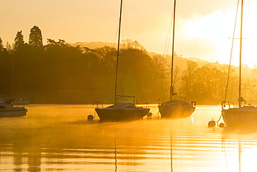 Sailing boats on Lake Windermere at sunrise with will o wisp mist, Waterhead, Ambleside, Lake District National Park, Cumbria, England, United Kingdom, Europe