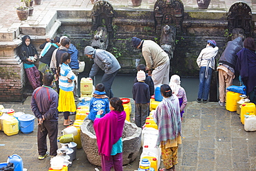 Locals queueing to fill up containers with water at a well in Patan's Durbar Square, UNESCO World Heritage Site, Kathmandu, Nepal, Asia