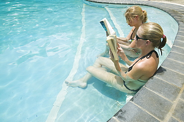 Women reading books in a swimming pool at the Walu Beach Resort on Malolo Island off Fiji, Pacific