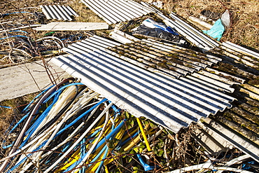 Illegally dumped asbestos sheeting with plastic wire sheath left by metal theives who stole the cabling and stripped the plastic off to get at the valuable copper wire, England, United Kingdom, Europe