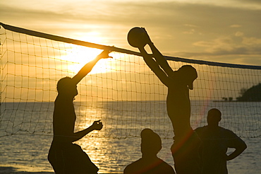 Fijian men playing beach volleyball at sunset at the Walu Beach Resort on Malolo Island off Fiji, Pacific