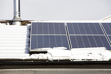 Solar panels partially covered in snow on a house roof in Ambleside, Lake District, Cumbria, England, United Kingdom, Europe