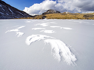 Wind drifted snow on Sprinkling Tarn at the head of  Borrowdale, frozen solid, looking towards Great End, Lake District, Cumbria, England, United Kingdom, Europe