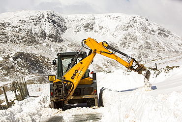 A JCB tries to clear a way through massive snow drifts blocking the Kirkstone Pass road above Ambleside in the Lake District, Cumbria, England, United Kingdom, Europe