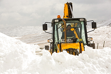 A JCB tries to clear a way through massive snow drifts blocking the Kirkstone Pass road above Ambleside in the Lake District, Cumbria, England, United Kingdom, Europe