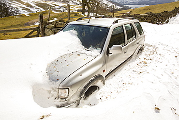 A four by four abandoned in massive snow drifts blocking the Kirkstone Pass road above Ambleside in the Lake District, Cumbria, England, United Kingdom, Europe