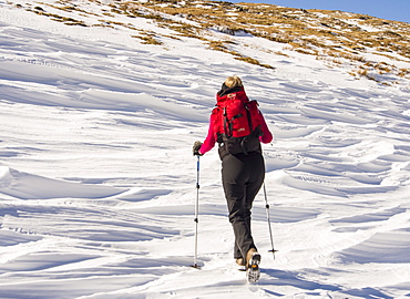 Snow shaped and scoured by a strong wind when it fell, and fell walker above Wrynose Pass in the Lake District, Cumbria, England, United Kingdom, Europe