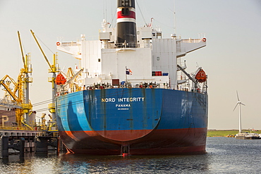 An oil tanker unloading at the docks, with a wind turbine behind, Amsterdam, Netherlands, Europe