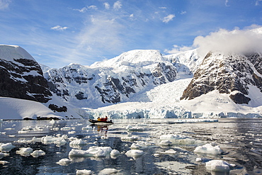 A zodiak from an expedition cruise amongst stunning coastal scenery beneath Mount Walker in Paradise Bay off Graham Land on the Antarctic Peninsular. the Peninsular is one of the most rapidly warming places on the planet.