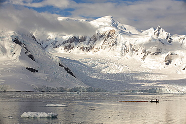 Members of an expedition cruise to Antarctica sea kayaking in Paradise Bay beneath Mount Walker on the Antarctic Peninsular. The Antarctic Peninsular is one of the most rapidly warming areas on the planet.