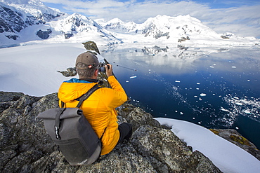 A passenger from an Antarctic cruise ship amongst stunning coastal scenery beneath Mount Walker in Paradise Bay off Graham Land on the Antarctic Peninsular. The Peninsular is one of the most rapidly warming places on the planet.