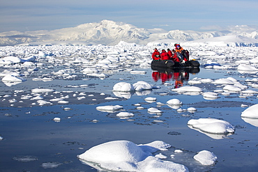 Members of an expedition cruise to Antarctica in a Zodiak in Fournier Bay in the Gerlache Strait on the Antarctic Peninsular. The Antarctic Peninsular is one of the most rapidly warming areas on the planet.