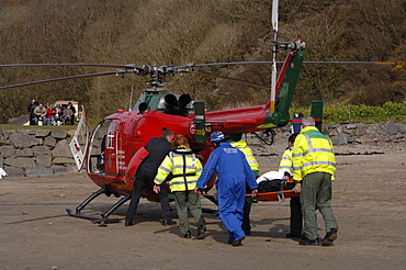 Wales Air Ambulance helicopter and crew carrying a casualty on a stretcher at Solva harbour, Solva, Pembrokeshire, Wales, UK, Europe