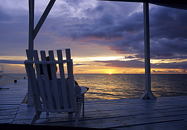 Person sitting in wooden chair watching sunset, Belize Barrier Reef, Caribbean      (rr)