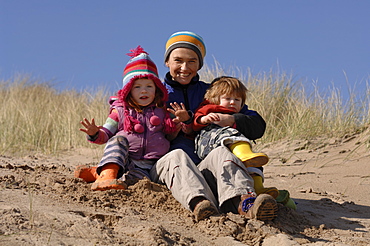 Mother and son and daughter playing in sand dunes, Broad Haven South, Stackpole, Pembrokeshire, Wales, UK, Europe