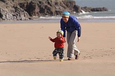 Mother and young son running on beach, Broad Haven South, Stackpole, Pembrokeshire, Wales, UK, Europe