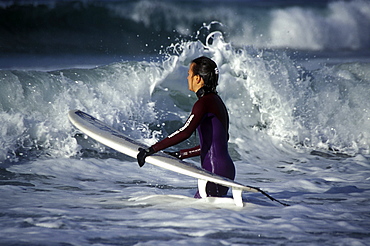 Young woman surfing, Musslewick beach, Pembrokeshire, Wales, UK