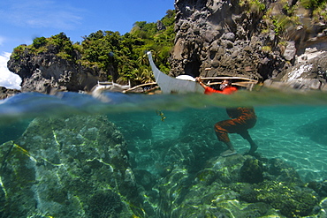 Fisherman wearing orange jumpsuit cleans his bangka, or traditional Philippino boat, Apo Island, Negros, Philippines, Southeast Asia, Asia