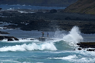 Waves crashing near fishermen at enseada da Caieira, Fernando de Noronha, Pernambuco, Brazil.   (rr)