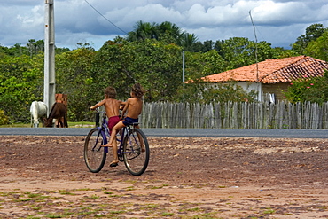 Kids cycling around highway, Sangue, Maranhao, Brazil, South America