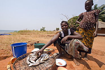 Lady preparing fish for meal with young girl, Talpia, Zambia, Africa