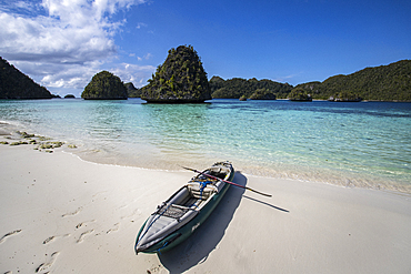 Karst limestone formations and lagoon in Wayag Island with the photographer's kayak, Raja Ampat, West Papua, Indonesia, Southeast Asia, Asia