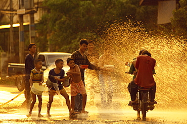 People on a motorbike being showered with water by men and boys during the Songklan Festival in Thailand, Southeast Asia, Asia