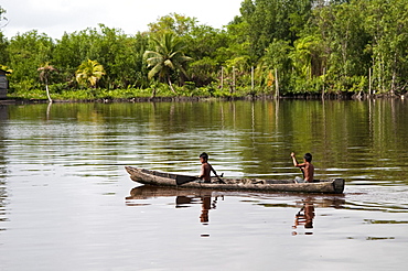 Amerindian boys paddling dugout canoe, Maharuma, Guyana, South America