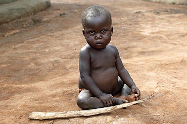 An IDP camp (internally displaced people) in Amuru district of Northern Uganda has been created to accommodate the mass of Ugandan refugees fleeing the LRA (Lords Resistance Army) who are fighting the Ugandan government and its people.  Here a young child has found a stick to play with. Amuru, Uganda, East Africa