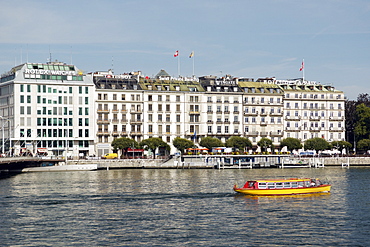 Tourist river boat cruises past luxury brand companies on Quai du Mont Blanc, Geneva. Geneva, Switzerland