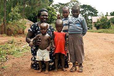 Proud mother shows off her children for a photo opportunity, on the road near their home.  They are without dad who will be out working.  Gulu Town, Uganda. Gulu Town, Uganda, East Africa