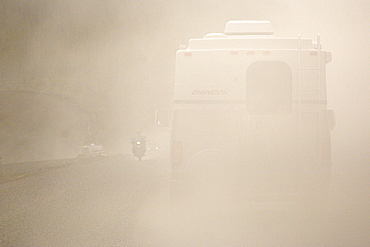 Following an RV through a heavy cloud of dust generated by heavy traffic on a gravel road.  Clearly see is a motorbike coming towards us on other side of the road. The Interior, Alaska, USA