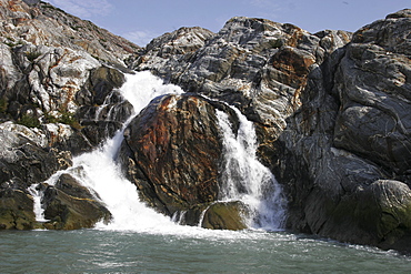 Glacier meltwater forms a small waterfall in Tracy Arm in southeast Alaska, USA.