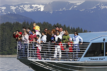 Whale watchers on the bow of a commercial whale watching operation looking for humpback whales in Stephen's Passage just outside Juneau, Southeast Alaska. No model or property releases.