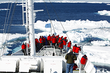 The National Geographic Endeavour breaking through ice floes in the Weddell Sea around the Antarctic Peninsula. Guests are on the bow watching the process.