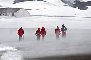 Lindblad guests walking along the beach in Whalers Bay in Port Foster inside the caldera of Deception Island, south Shetland Islands, Antarctica