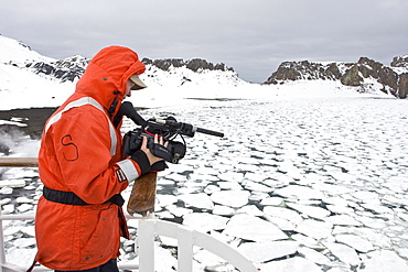 Crew videographer Anika of the Lindblad Expedition ship National Geographic Endeavour at work in the crows nest on Deception Island in Antarctica.