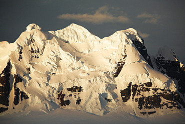 Sunset on snow covered peaks in the magnificent Lemaire Channel, Antarctica.